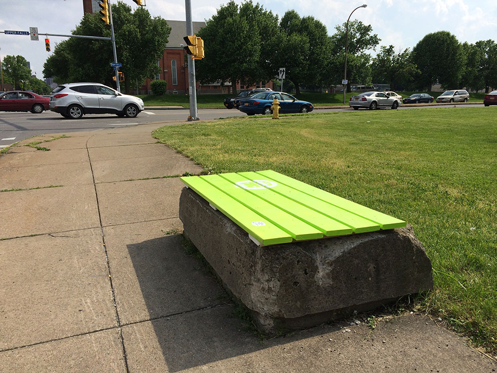 An old tree protector wall on Joseph Avenue, reborn as a bus stop bench.