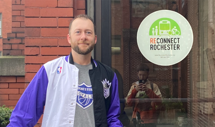 Jesse Peers (white man) stands in front of Reconnect Rochester door at the Hungerford Building.