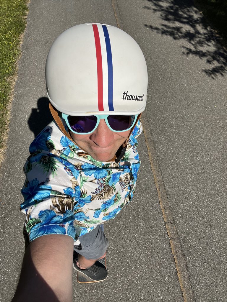 Selfie of a man skateboarding with a helmet and sunglasses on